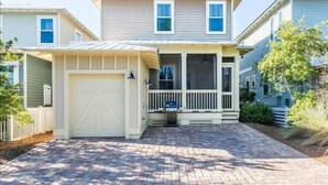 A two-story house with a covered front porch, a garage, and a brick driveway.