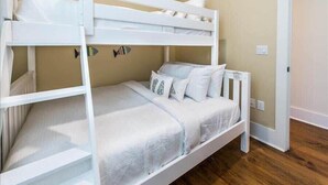 A bunk bed with white bedding and pillows, a fish decoration on the wall, and wooden flooring.