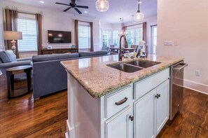 A modern kitchen with granite countertops, a built-in sink, and light blue cabinetry. - 6-Seat Golf Cart & 4 Bikes! 3 Min Walk to 2 Pools! Nature Trails to the Beach! ~ Sea Blessings at NatureWalk on 30A (Santa Rosa Beach)