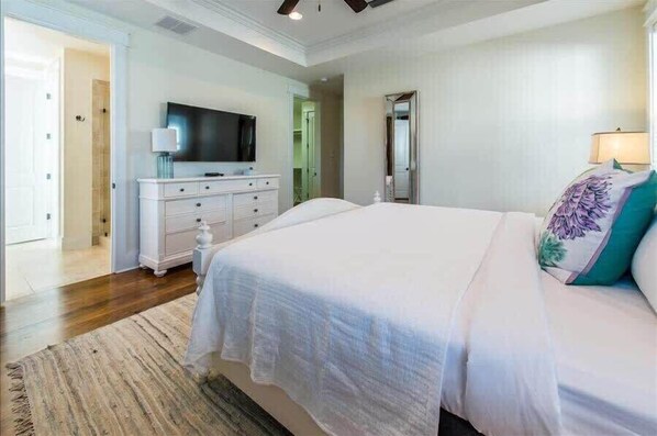 A bedroom with a large bed, a TV on a dresser, and a mirror.