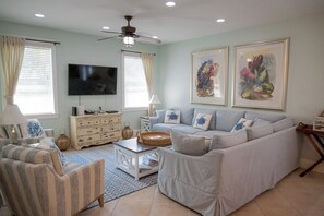 A living room with a sofa, armchairs, a coffee table, a TV, and artwork on the walls.