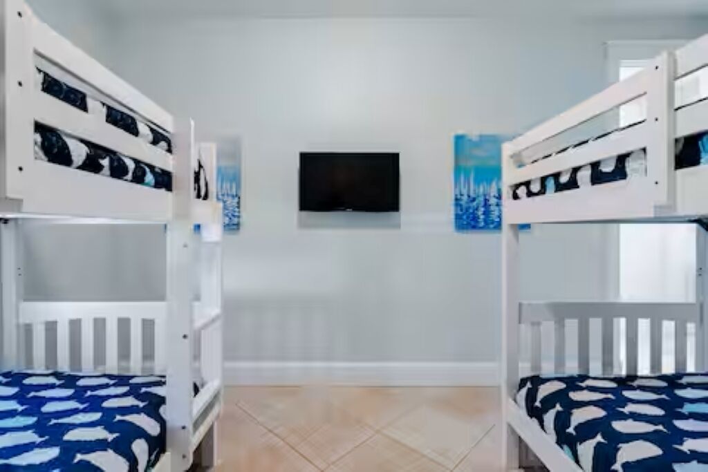 A room with bunk beds, a flat-screen TV, and artwork on the wall.