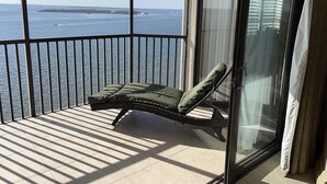 A balcony with a single lounge chair, a view of the sea, and a glass door. - Beachfront 10th Floor Resort Condo -  Breathtaking views  (Fort Myers)