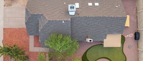 An aerial view of a residential property with a swimming pool, patio furniture, and a landscaped lawn.