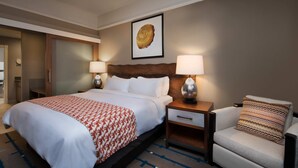 A hotel room with a large bed, two bedside tables with lamps, a chair, and a framed artwork on the wall. - Marriott Summit Watch Studio (Park City)