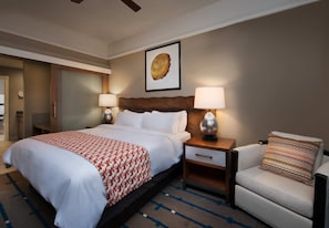 A hotel room with a large bed, two bedside tables with lamps, a chair, and a wall-mounted artwork.