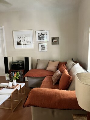 Una sala de estar con un sofá, una mesa de centro, una estantería y fotografías enmarcadas en la pared.