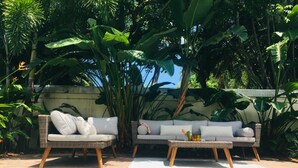 A poolside area with two wicker sofas and a small table, surrounded by lush tropical plants. - DELRAY BEACH  Private Pool, Close To Sea (Delray Beach)