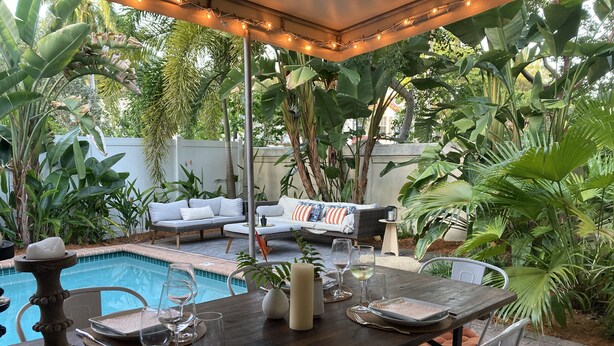 A poolside dining area with a table set for two, surrounded by lush tropical plants. - DELRAY BEACH  Private Pool, Close To Sea (Delray Beach)