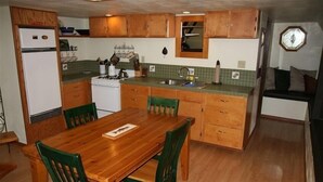 Une cuisine de taille réduite, dotée de meubles de rangement en bois, d’une cuisinière et d’une table à manger avec des chaises.