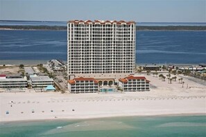 A large hotel with multiple floors, a beach in the foreground, and a body of water in the background. - Fantastic, New 10% Summer DISCOUNT for Beautiful Ocean Resort,Lowest Prices (Pensacola Beach)