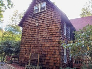 A rustic wooden cabin with a shingled exterior, a small porch, and a sign indicating it is a guesthouse. - FIELDSTONE AND LOG HOME ON BEECH.   
Ski season dates available at 2024 prices! (Beech Mountain)