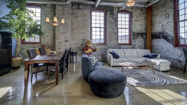 A spacious living area with a dining table, sofa, and a large statue.