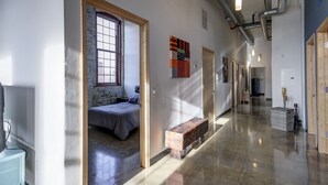 A hallway with a bed, a bench, and a wall-mounted artwork.