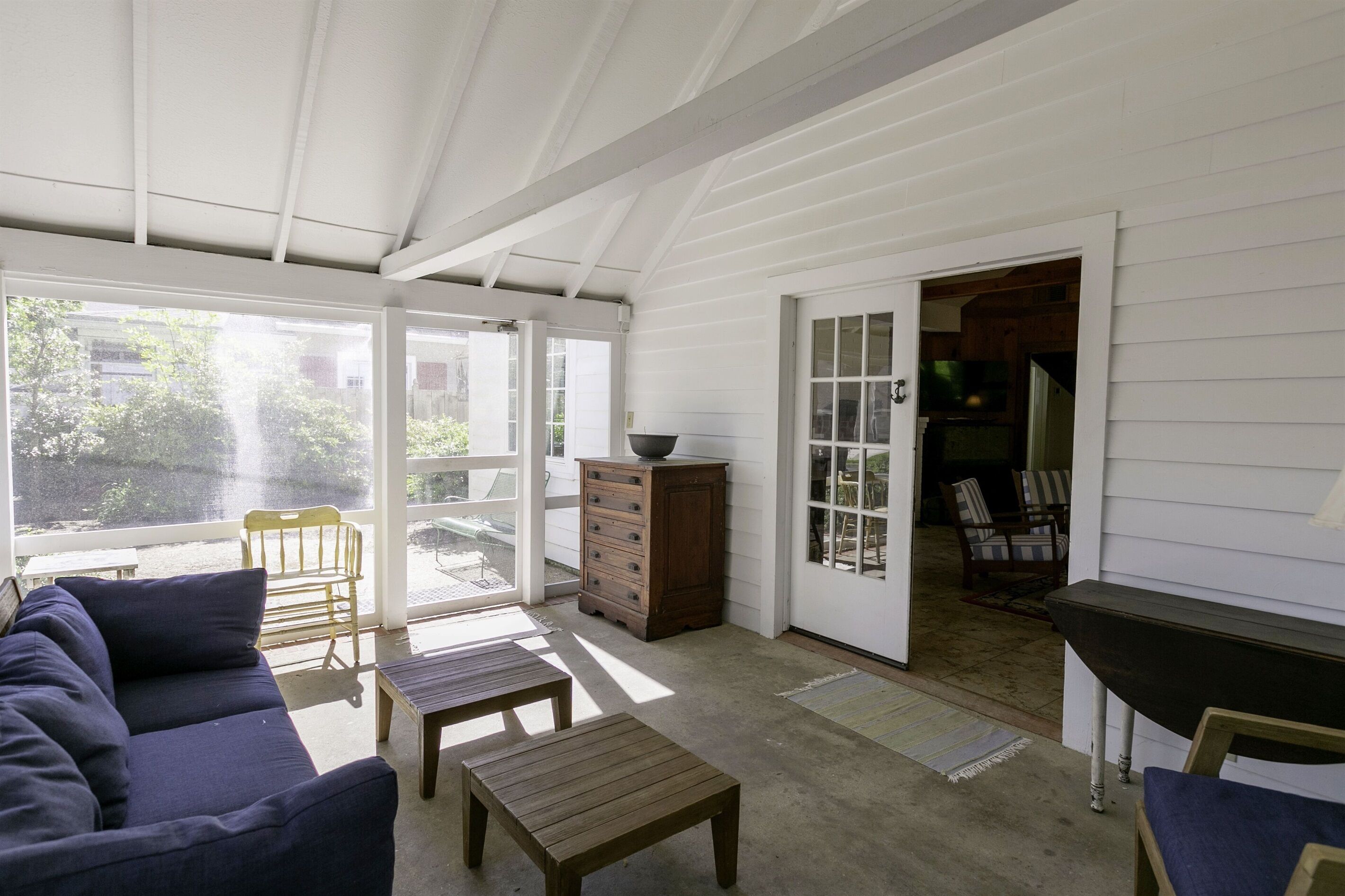 A covered patio area with a sofa, wooden table, and chairs.
