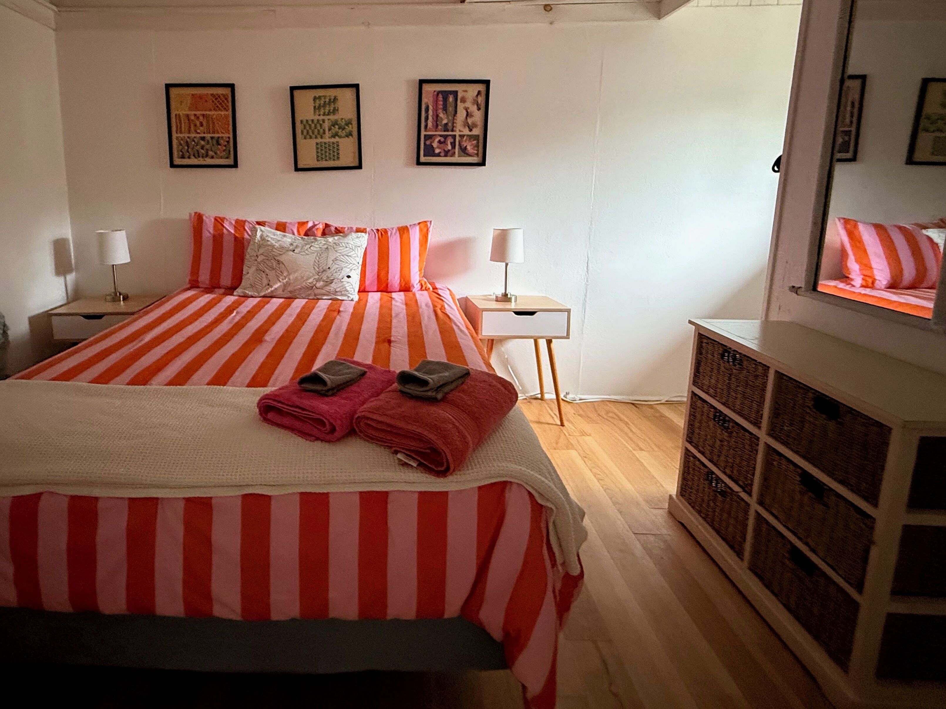 Ein Hotelzimmer mit einem Bett, zwei Nachttischen, Holzboden und einer Wand mit gerahmten Bildern.