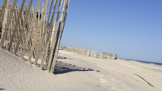 A sandy beach with wooden fences and a clear blue sky.
