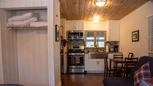 A compact kitchen with white cabinetry, stainless steel appliances, and a dining area with a dark-colored sofa.