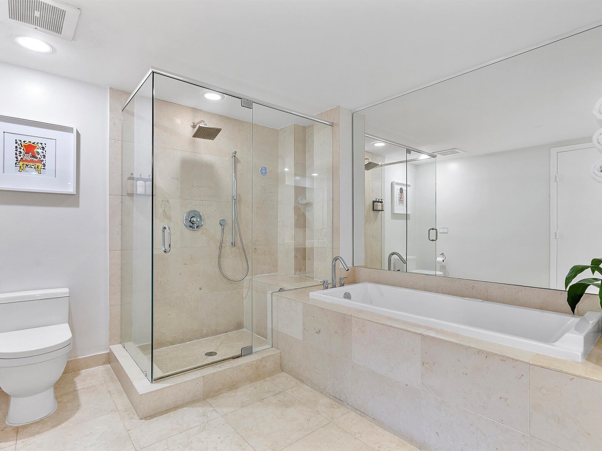 A modern bathroom with a glass-enclosed shower, a large bathtub, and a toilet.