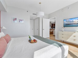 Une chambre à coucher moderne avec un lit, une table de chevet et un téléviseur.
