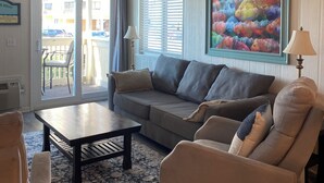 Ein Wohnzimmer mit einer Couch, Sesseln, einem Couchtisch und einem Bild an der Wand.