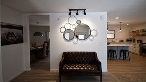 A modern living room with a leather sofa, a dining area with wicker chairs, and a kitchen with a wooden countertop and bar stools. - Luxury Ranch House on Continental Golf Course, Great for families, Remodeled.  (Flagstaff)