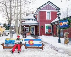 A bench with a colorful design, a red building with a sign, and a snowy environment.