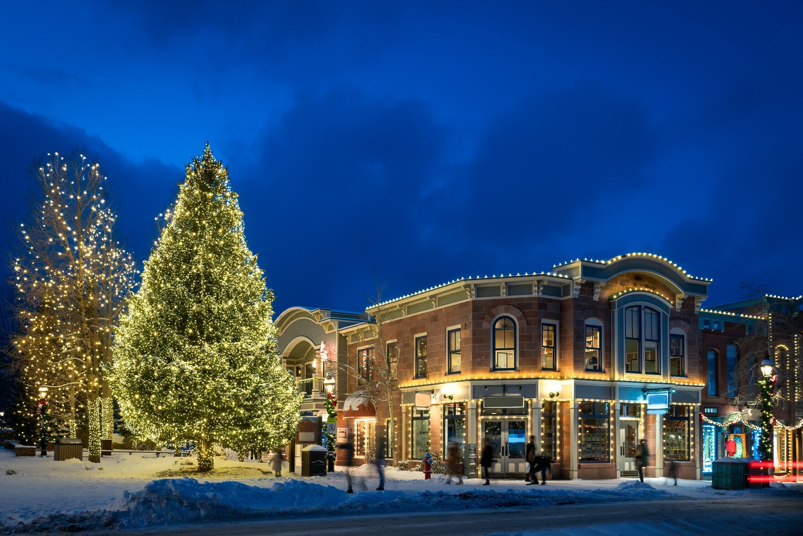 A historic building with a snow-covered street and Christmas lights.
