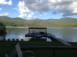 A lakeside dock with a covered seating area, a boat, and a row of chairs. - Priest lake waterfront cabin (Nordman)