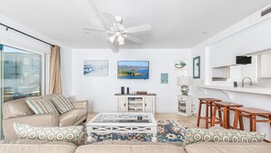 A living room with a beige sofa, a coffee table, a TV, and a ceiling fan. - Ocean View Corner Home (lower unit)  - 1 house from the Beach! - Walk to all the Hot Spots! (Newport Beach)