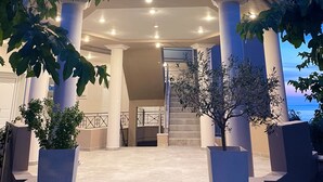 A multi-story building with a balcony, columns, and a staircase leading to an entrance.
