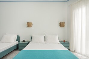 Ein Schlafzimmer mit zwei Betten, einer türkisblauen Tagesdecke und zwei Nachttischen mit Korbwäsche.