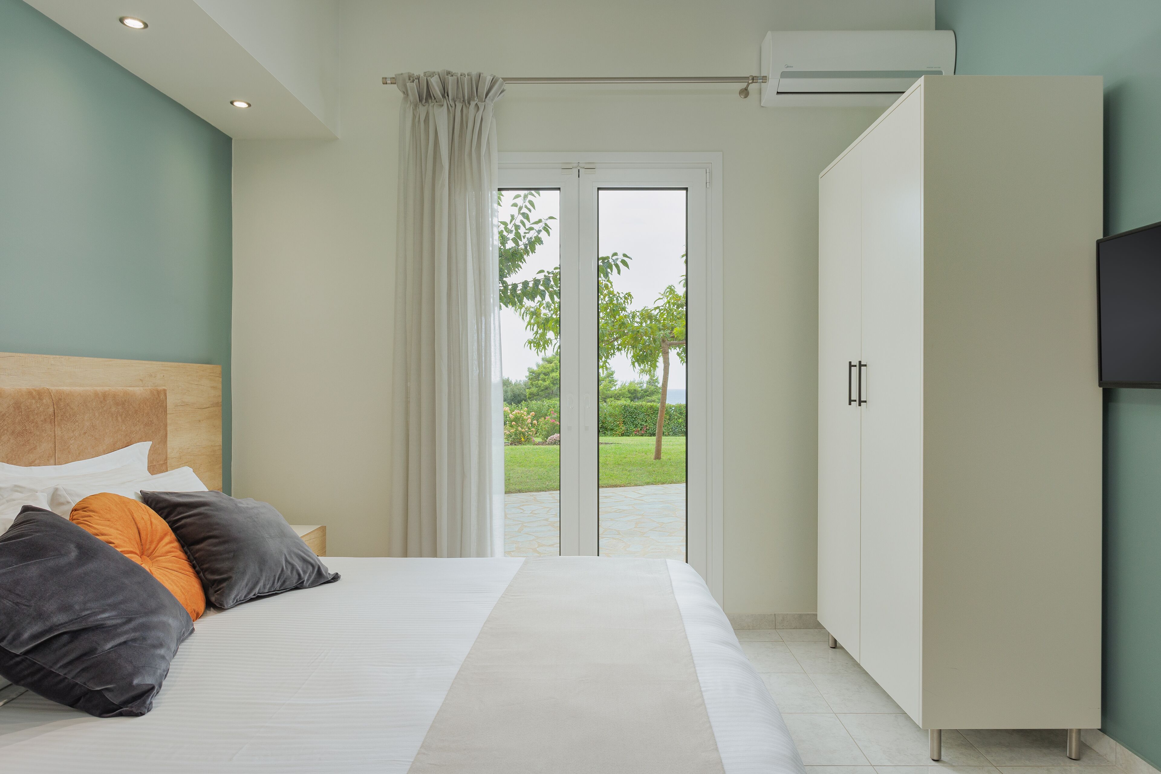 Quarto com cama, guarda-roupa e televisão.