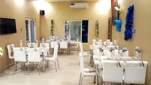 A dining area with multiple tables and chairs, air conditioning units, and decorative garlands. - Noahgarden (Cotonou)