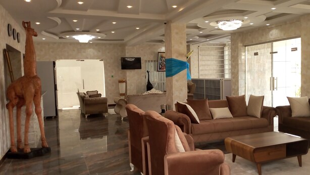 A spacious living area with a modern design, featuring a large sofa set, a coffee table, and a giraffe sculpture. - Noahgarden (Cotonou)