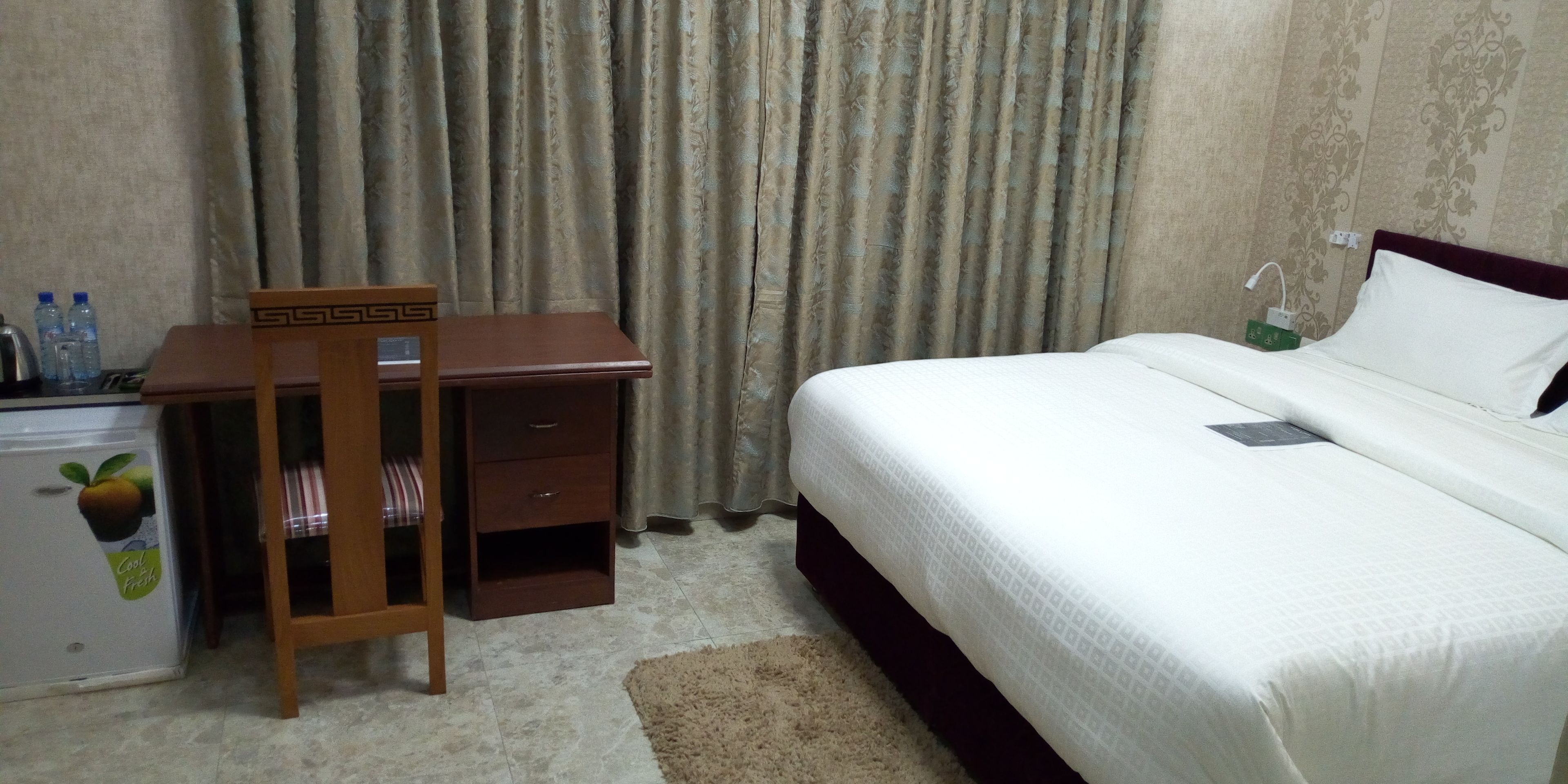 A hotel room with a bed, a desk, and a refrigerator.