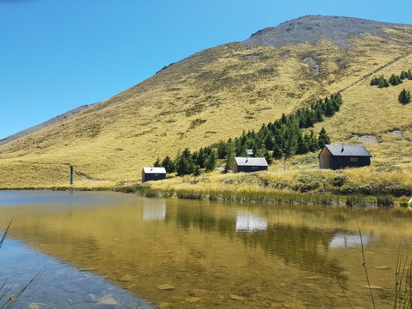 A tranquil lakeside scene with three cabins, clear water reflecting the surroundings, and a mountain in the background. - Lake Stella Mountain Retreat (Lyford)
