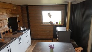 Una cocina moderna con detalles de madera, una isla central con un florero y un ventanal que proporciona luz natural.