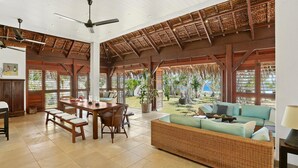A spacious indoor area with a high ceiling, a dining table with chairs, a sofa, and a ceiling fan.
