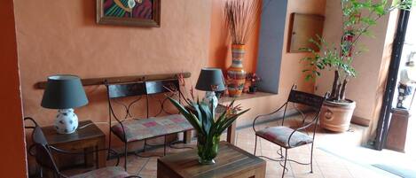 A cozy indoor seating area with a wooden bench, two chairs, a small table, and a potted plant.
