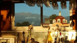 A kitchen with a large window overlooking a mountain and a building with a red dome. - Hotel Posada San Jerónimo (Coatepec)