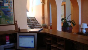 A reception area with a computer monitor, a map on the wall, and a staircase leading to an upper level. - Hotel Posada San Jerónimo (Coatepec)
