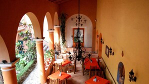 An indoor dining area with tables and chairs, arches, and a chandelier. - Hotel Posada San Jerónimo (Coatepec)