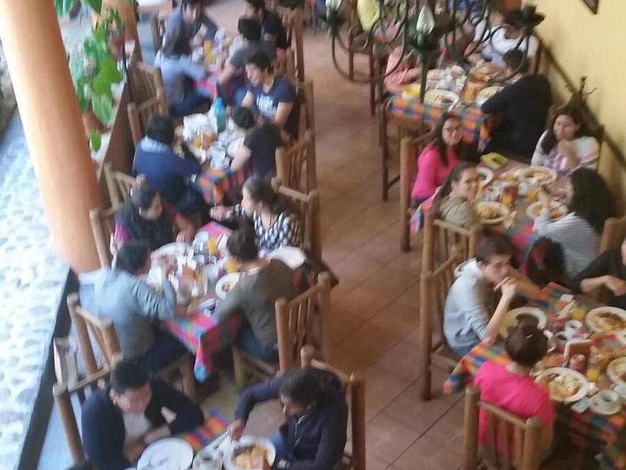 Ein Essbereich mit mehreren Tischen und Stühlen, Personen sitzen und essen.