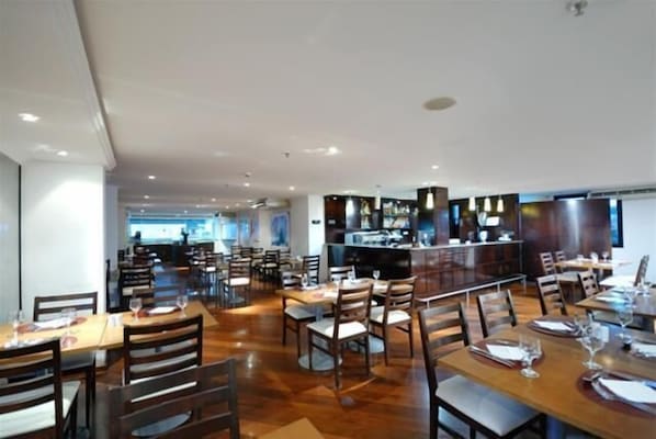 Un restaurant spacieux avec de nombreuses tables et chaises, un bar et une cuisine située à l’arrière.