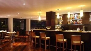 Eine Bar mit Holzboden, Barhocker und Pendelleuchten.
