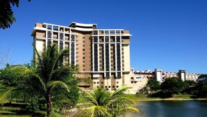 Ein modernes Hotel mit mehreren Etagen, einem Innenhof und einem Wasserspiegel im Vordergrund.