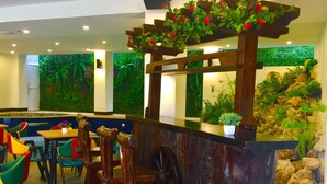 A restaurant with wooden chairs, a counter, and green foliage decorations. - El Puerto Boracay (Boracay Island)