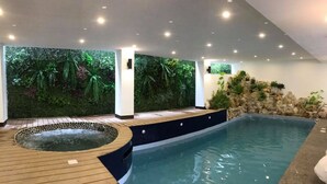 An indoor swimming pool with a wooden deck, a hot tub, and a wall with artificial greenery. - El Puerto Boracay (Boracay Island)
