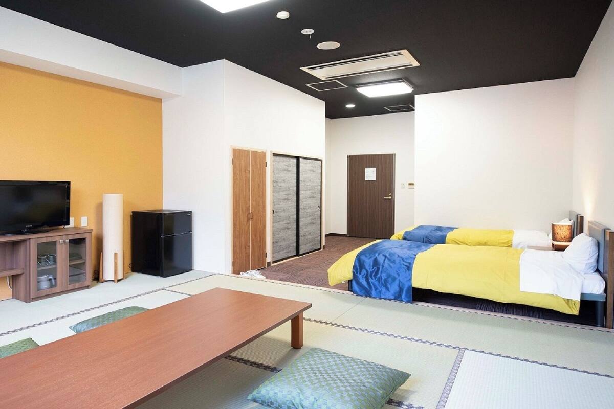 A hotel room with a bed, a TV, a small table, and a cabinet.